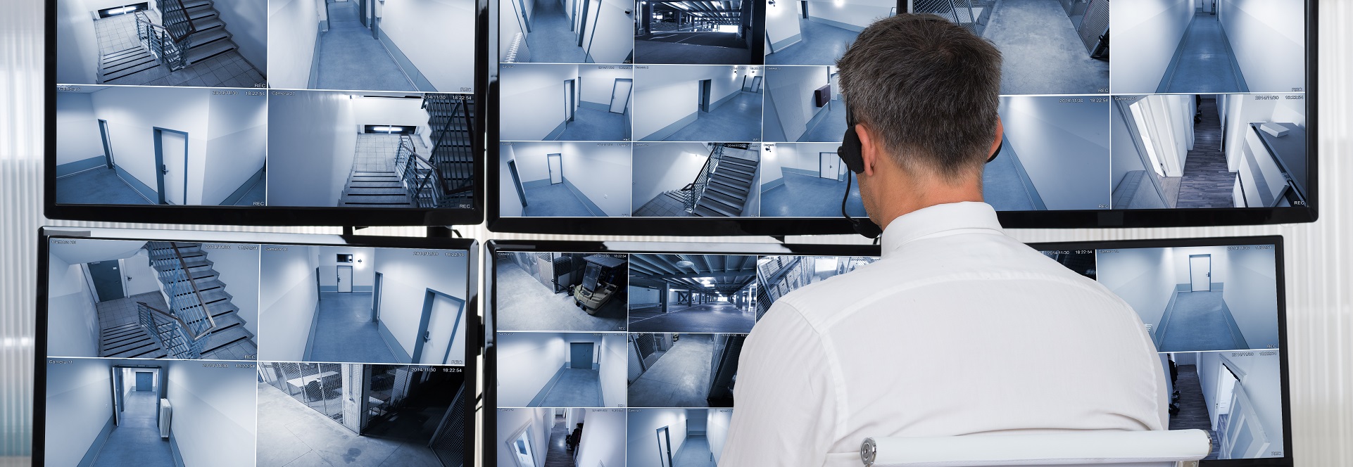 Security System Operator Looking At CCTV Footage At Desk
